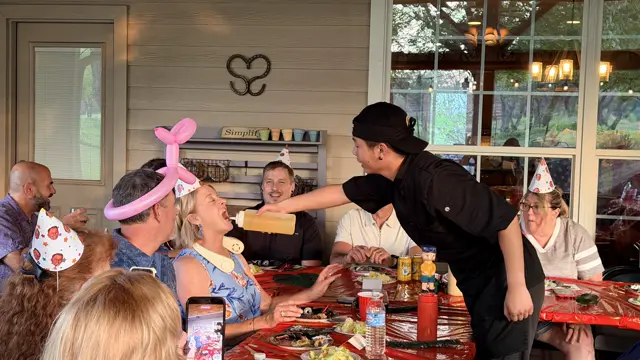The chef squirts sake into a laughing guest's mouth